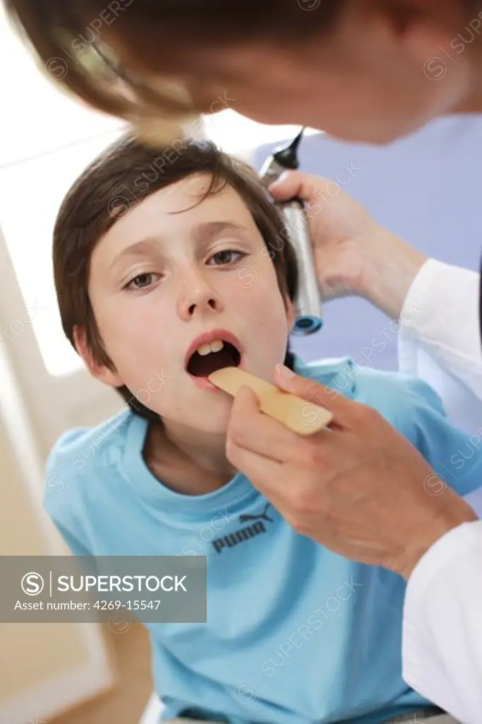 Doctor examining the throat of a 9 years old boy.