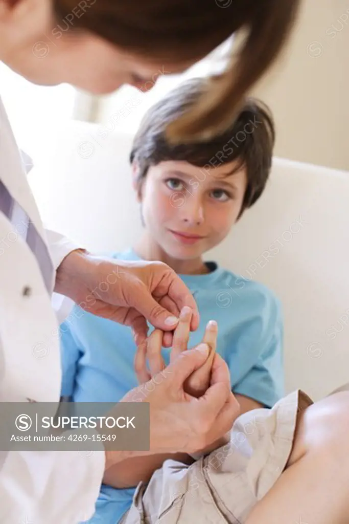 Doctor examining the hand of 9 years old child.