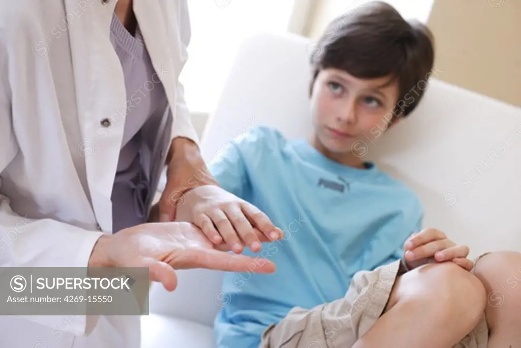 Doctor examining the hand of 9 years old child.