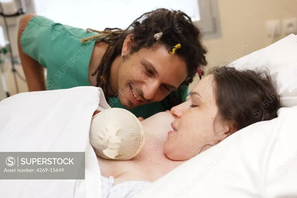 Mother and her newborn baby with father in labor room just after delivery. Obstetrics and gynaecology department, Saintonges hospital, Saintes, France.
