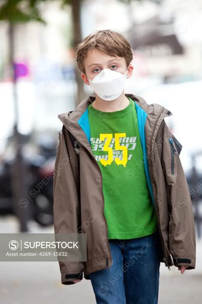 9 years old boy wearing a respiratory protective mask. The French Health Minister recommends to wear this protection mask in case of viral respiratory diseases (cold, bronchitis and flu).