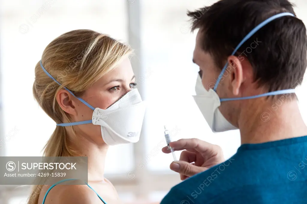 Woman receiving vaccination. General practitioner and patient wearing a respiratory protection mask during consultation with contagion hazard.