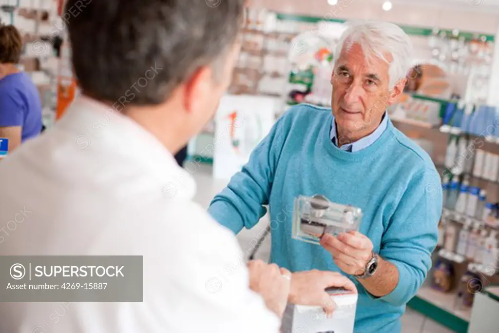 Man buying a blood glucose tester (glucometer) in a pharmacy for checking self glycemia.