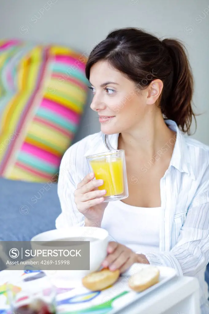Woman drinking a glass of orange juice for breakfast.