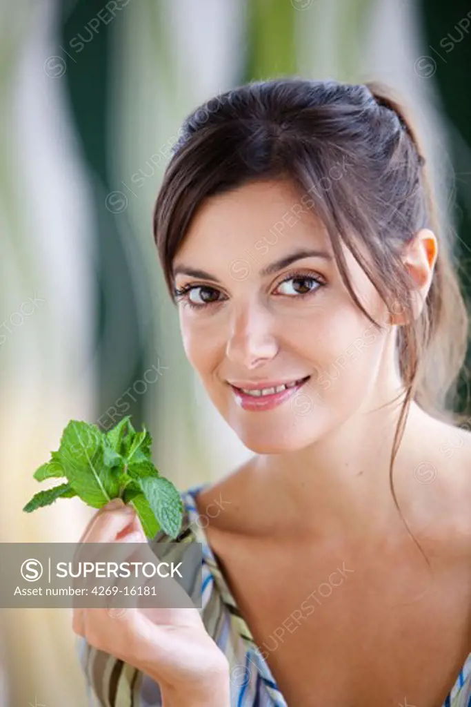 Woman smelling mint leaves (Mentha sp.)