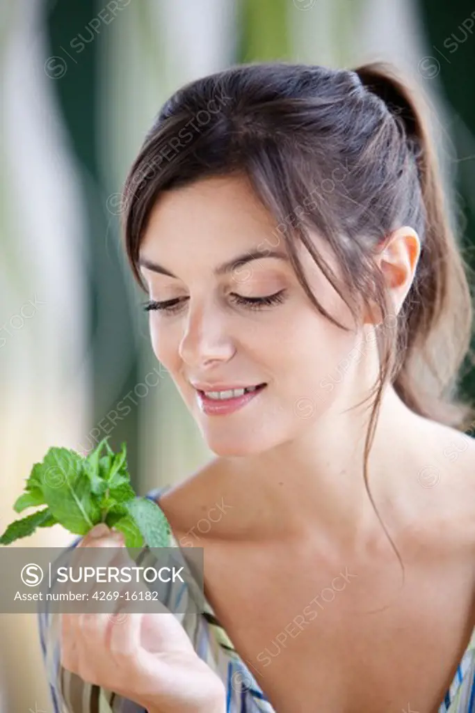 Woman smelling mint leaves (Mentha sp.)