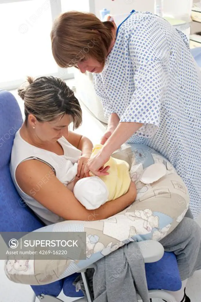 Mother breastfeeding her premature newborn baby with pediatric auxiliary nurse. Obstetrics and gynaecology department, Saintonges hospital, Saintes, France.