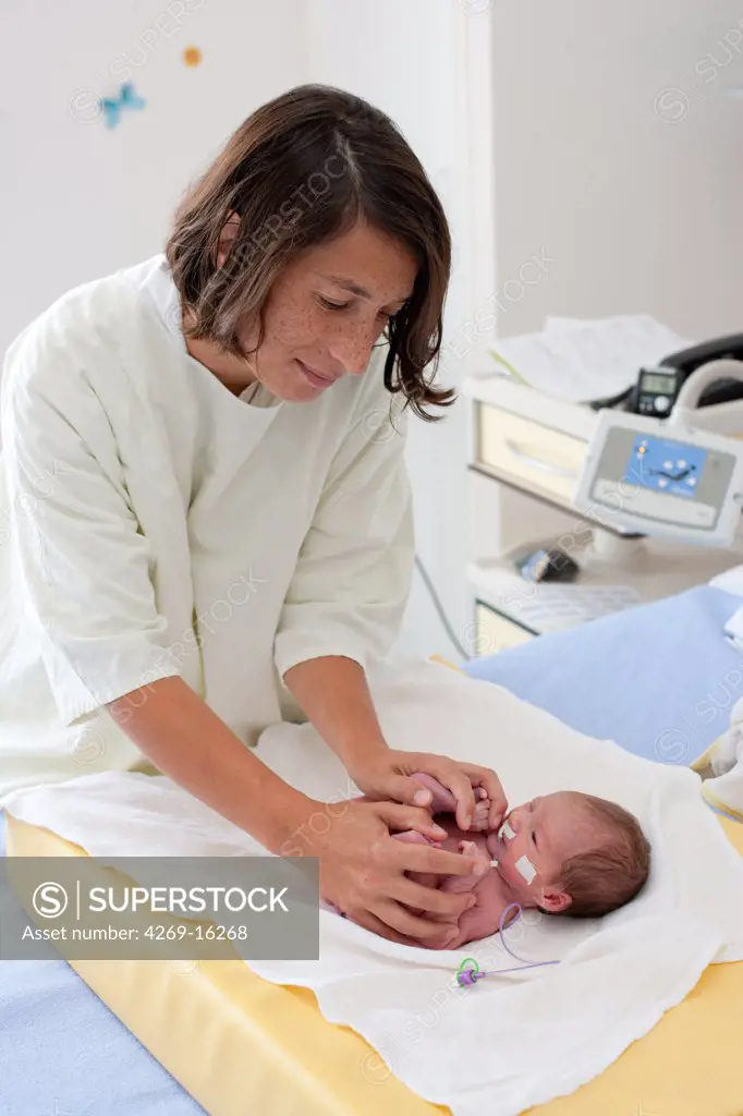 Pediatrician puts a premature newborn baby in fetal position to relax him. Obstetrics and gynaecology department, Saintonges hospital, Saintes, France.