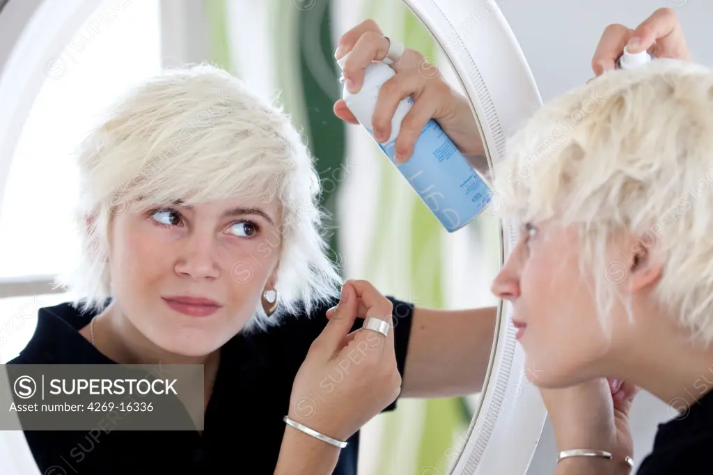 Teenage girl using hairspray.
