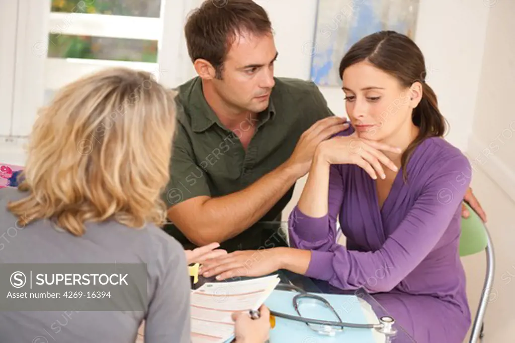 Doctor talks with a couple during consultation.