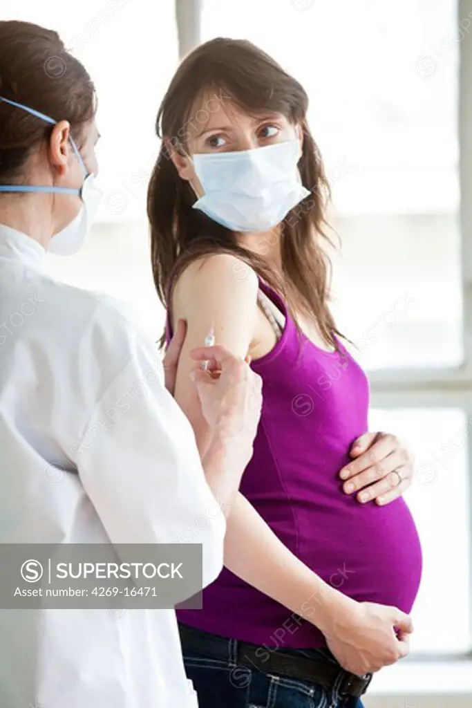 Pregnent woman receiving vaccination. Doctor and patient wearing a respiratory protection mask during consultation with contagion hazard.