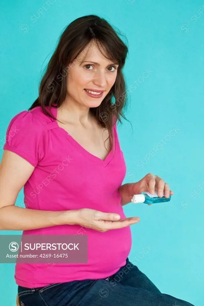 Pregnent woman washing her hands with hydroalcoholic gel, as recommended by the Minister of Health in case of viral respiratory diseases, common cold, influenza.