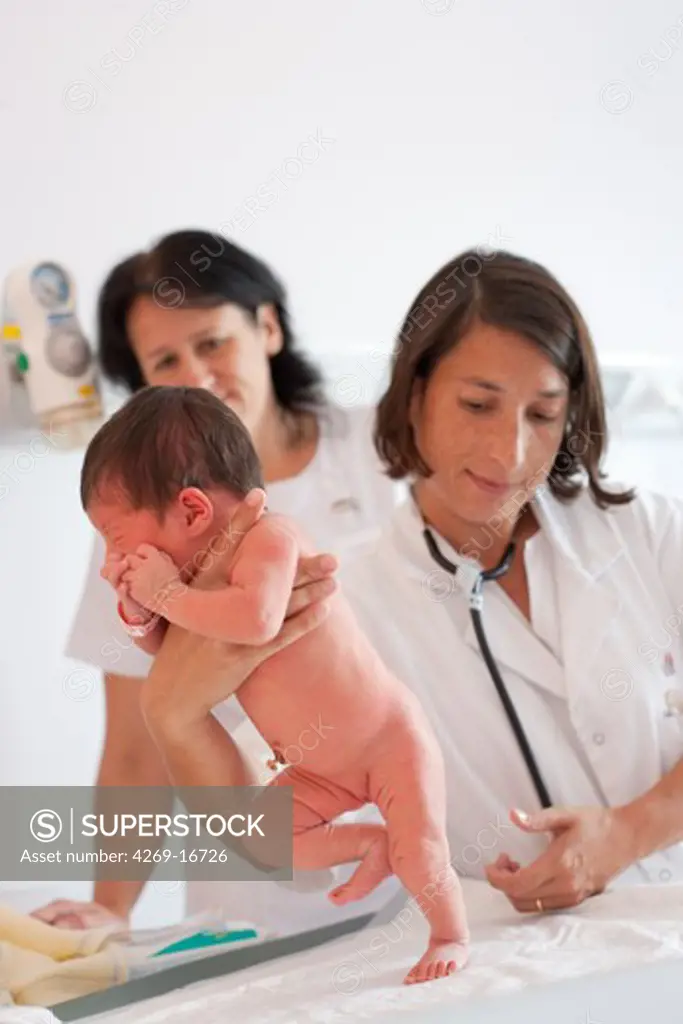 Pediatrician examining a newborn baby (stepping or walking reflex). Obstetrics and gynaecology department, Saintonges hospital, Saintes, France.