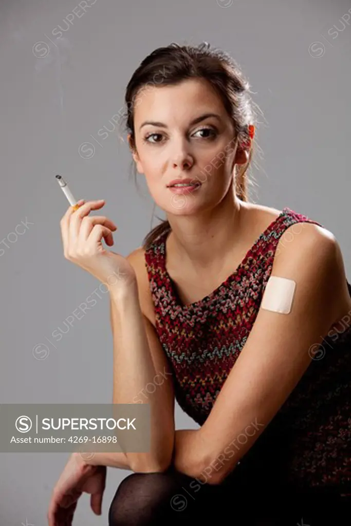 Woman with a tobacco control patch and smoking.