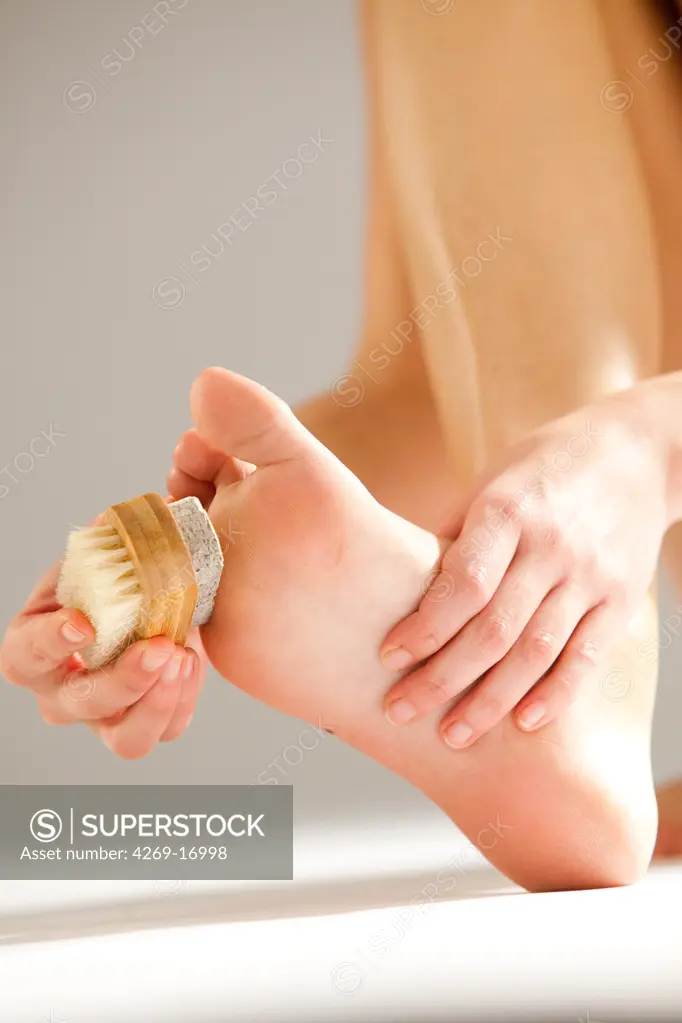 Woman removing hard skin on her foot with a foot file.