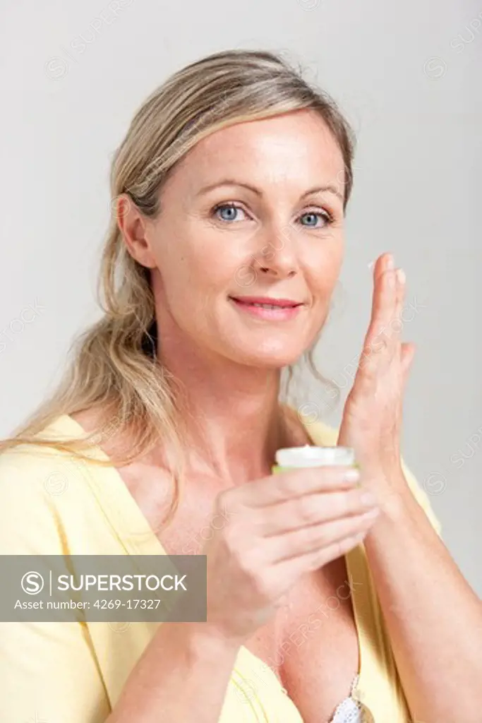 40 years woman applying antiwrinkle or moisturizing cream on her face.