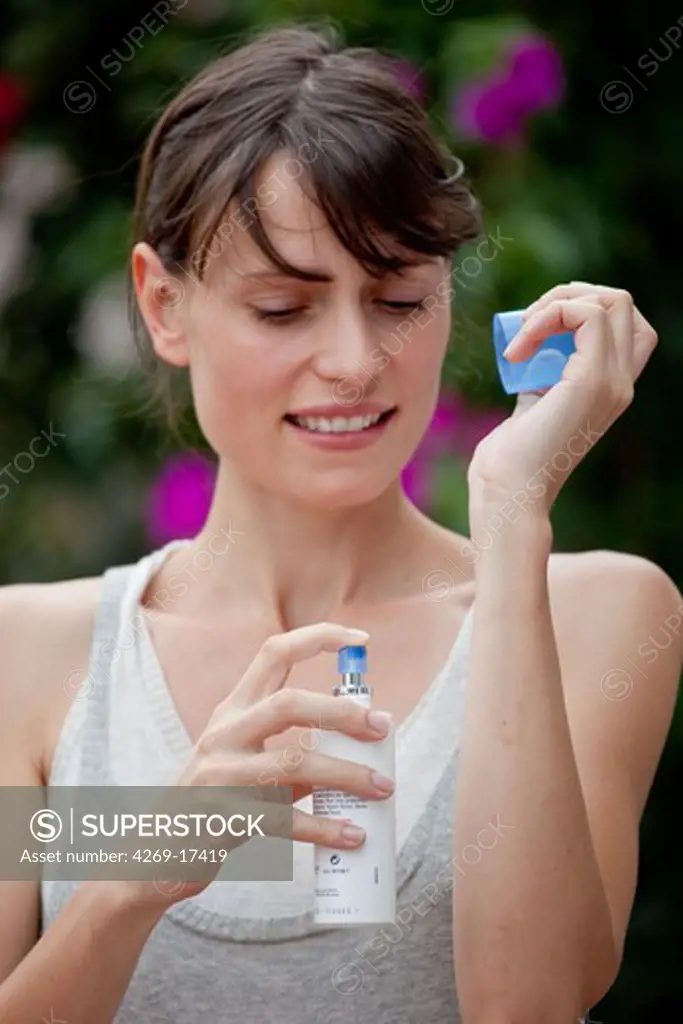 Woman applying spray against insect bites and itching.