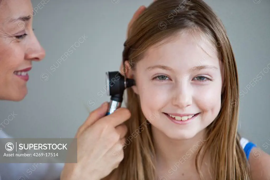 Doctor examining the ears of a 9 years old girl with an otoscope.