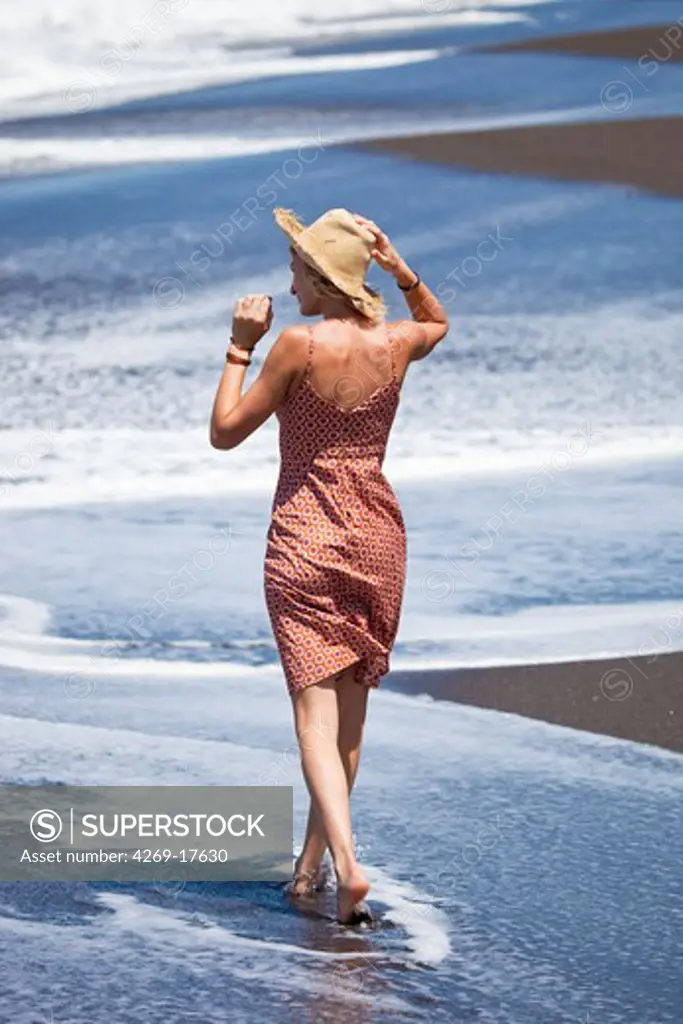 Woman walking along a beach.
