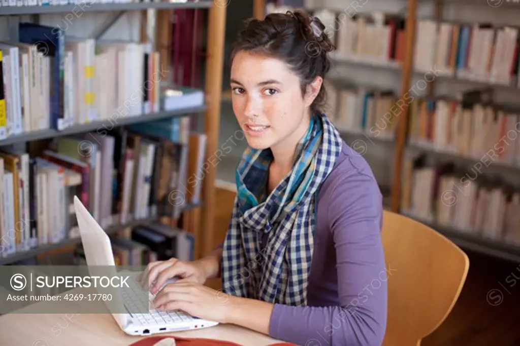 Young woman using a netbook in a library.