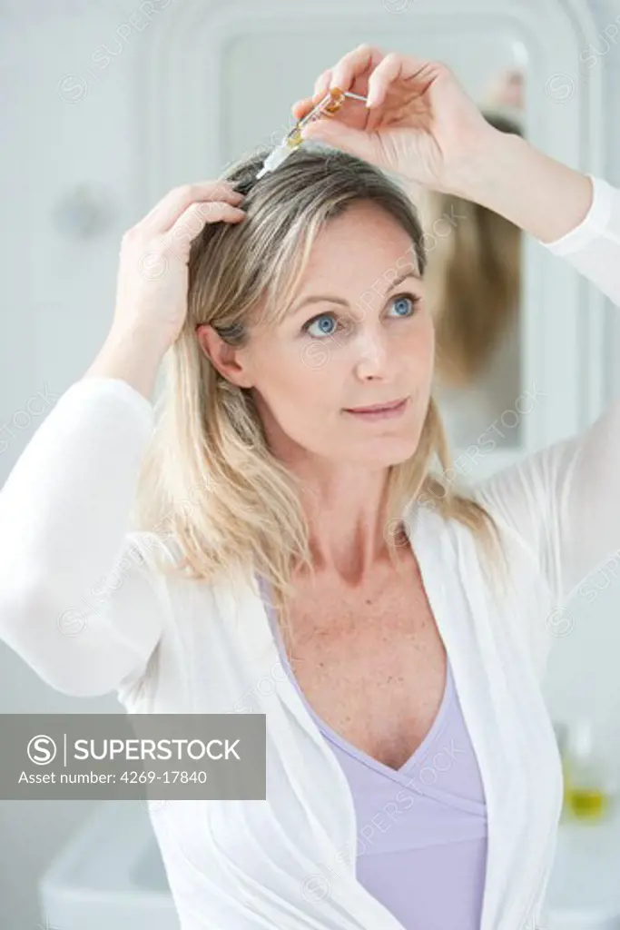 Woman applying hair lotion.