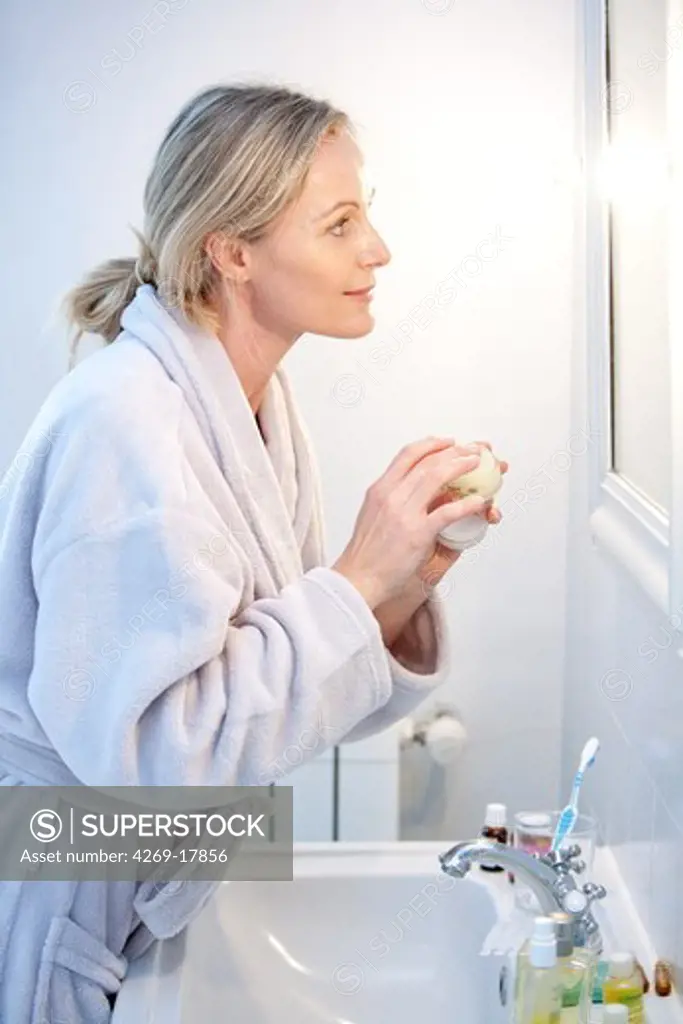 Woman applying moisturizing cream on her face.