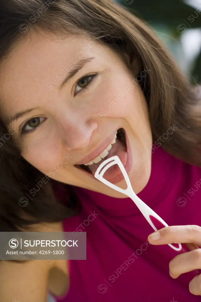 Woman brushing her tongue with a specific tongue-brush to eliminate the bacteria responsible for bad breath.