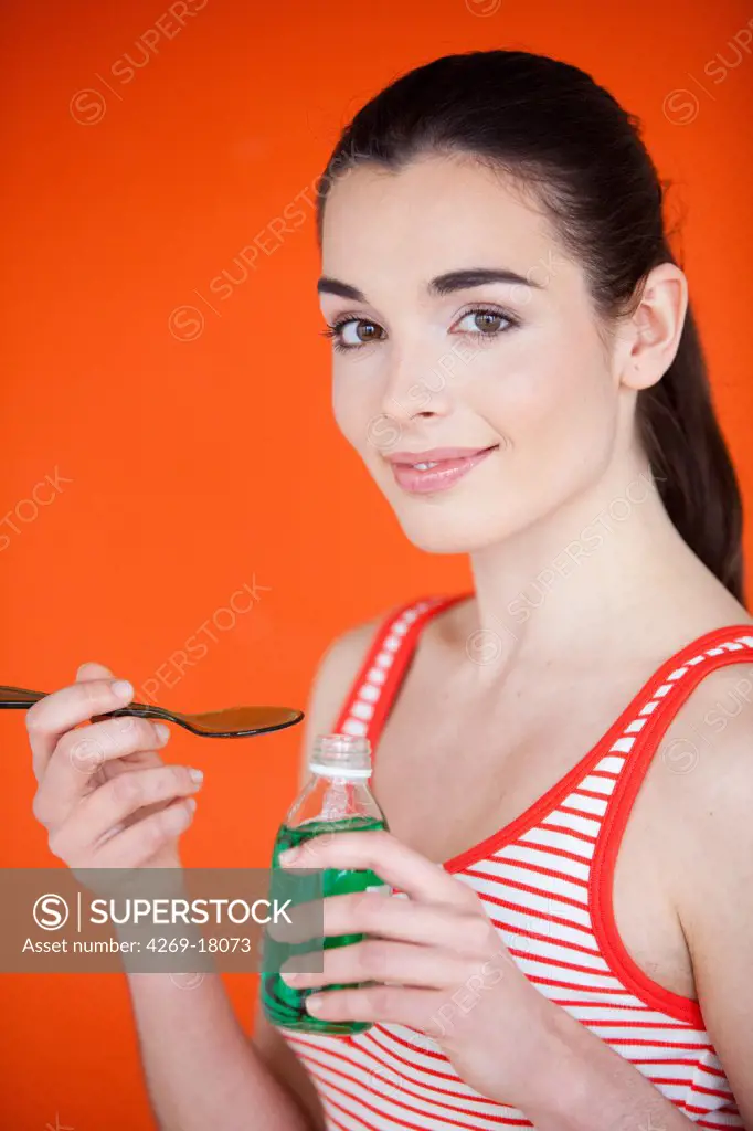 Woman taking syrup.