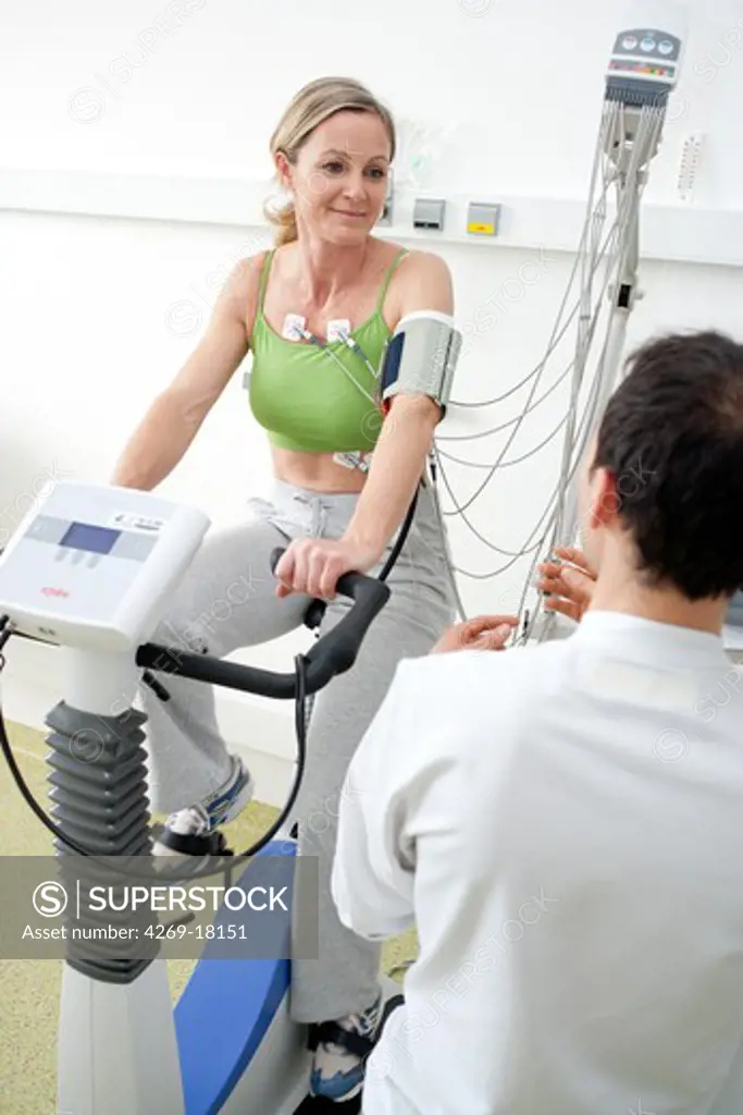 Patient doing monitored heart rehabilitation training exercises on ergometric bicycle. Limoges hospital, France.