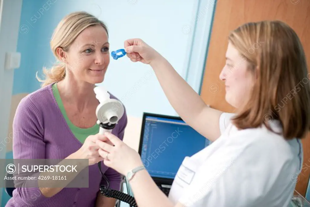 Woman undergoing a lung function test using a spirometer that measures the maximum rate at which air is expelled from the lungs. Respiratory diseases department, Limoges hospital, France.