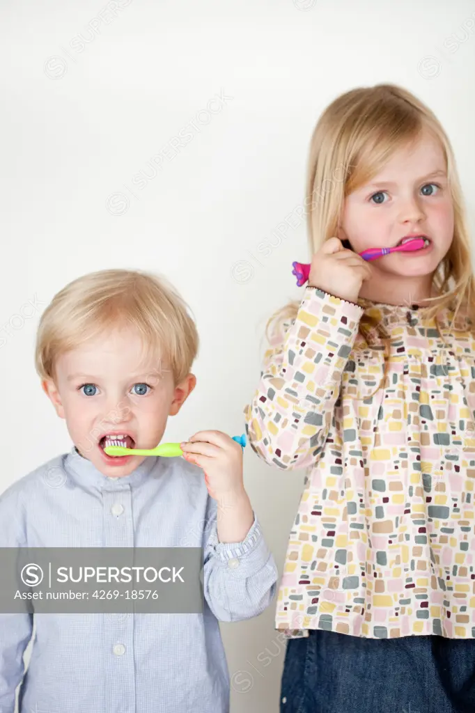 Brother and sister brushing their teeth.