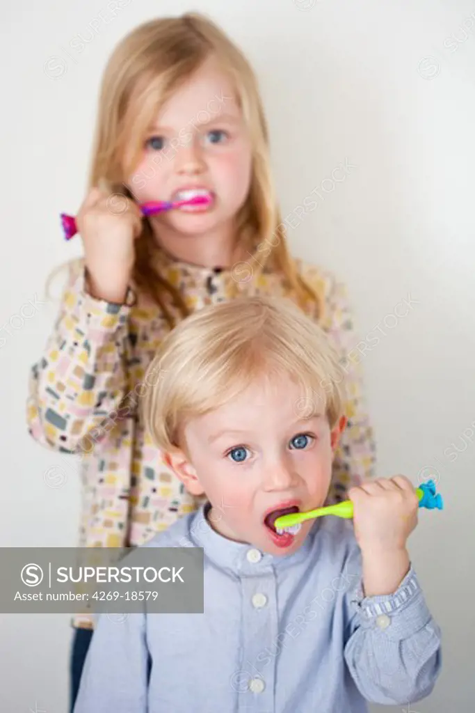 Brother and sister brushing their teeth.