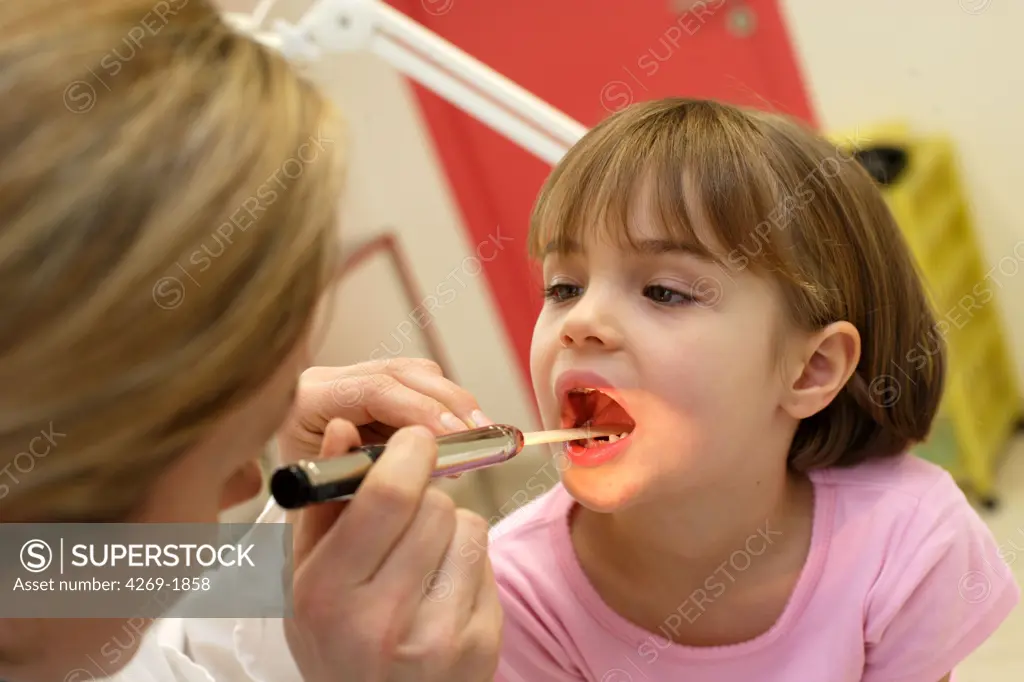 A pediatrician examines the throat of a 4 years old child.