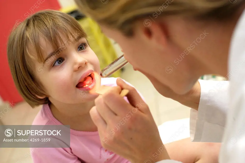 A pediatrician examines the throat of a 4 years old child.