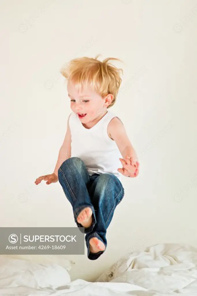 3 years old boy jumping on a bed.