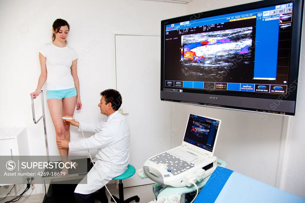 Woman undergoing a Doppler ultrasound (angiodynography) scan of the legs to study blood flow and explore potential deep vein thrombosis.