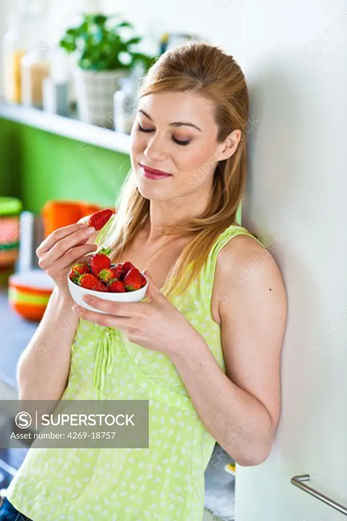 Young woman eating strawberries.