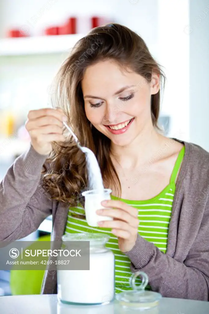 Woman adding sugar in yogurt.