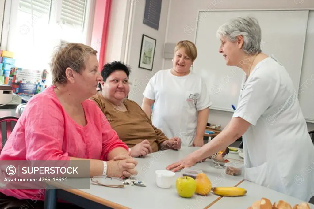 A nurse is holding a nutritional education workshop for obese patients. Limoges hospital offers its obese patients requiring hospitalization for five days for a multidisciplinary management of obesity. Department of Internal Medicine, Endocrinology, Diabetes and Metabolic Diseases. Limoges, France.