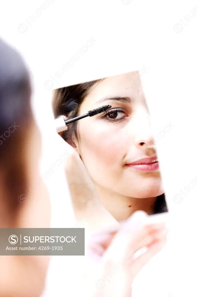 Woman applying mascara on her eyelashes.