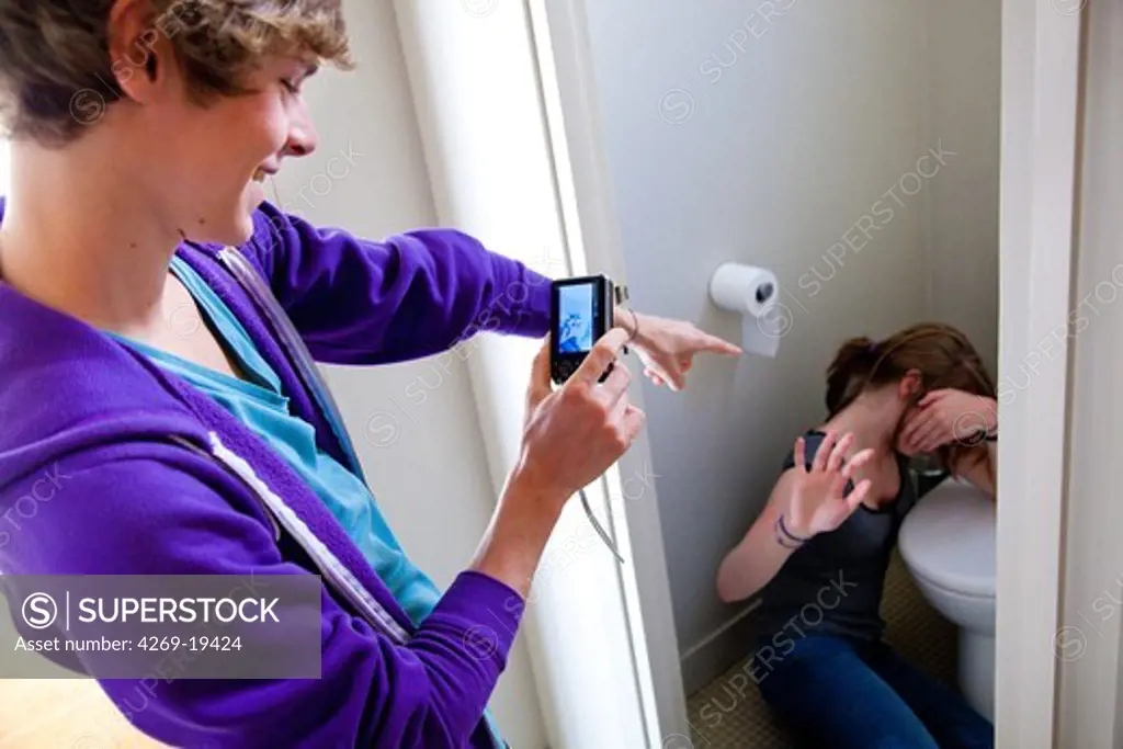 Teenage boy taking picture of a teenage girl at the toilets.