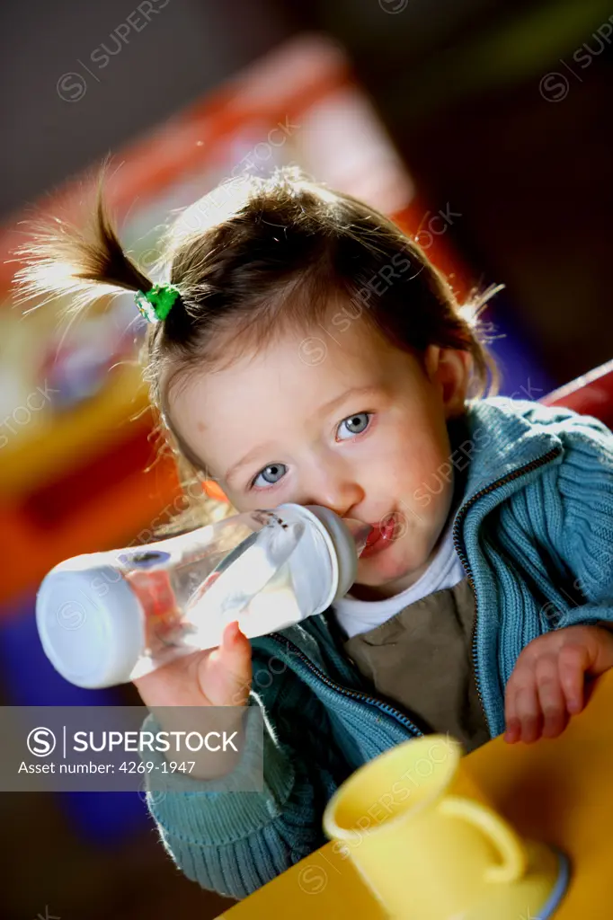 15 months old little girl drinking water from baby's bottle.