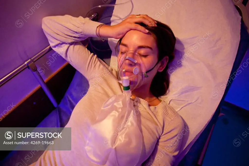 Woman suffering from headache undergoing oxygen therapy in a rest room. Treatment of facial vascular pain. Department of cephalea emergency, Pitié-Salpêtrière hospital, Paris, France.