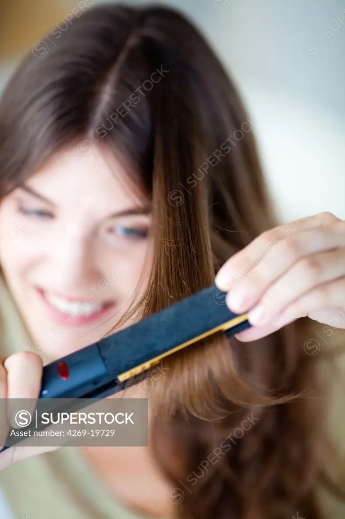 Woman using a hair straightener.