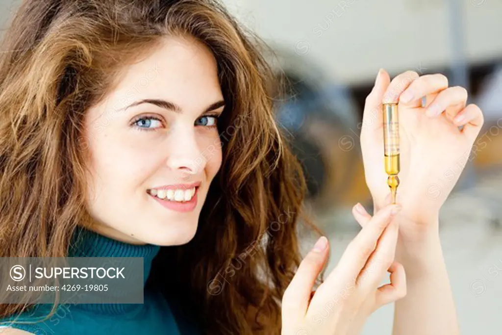 Woman holding glass ampoule of vitamin D.