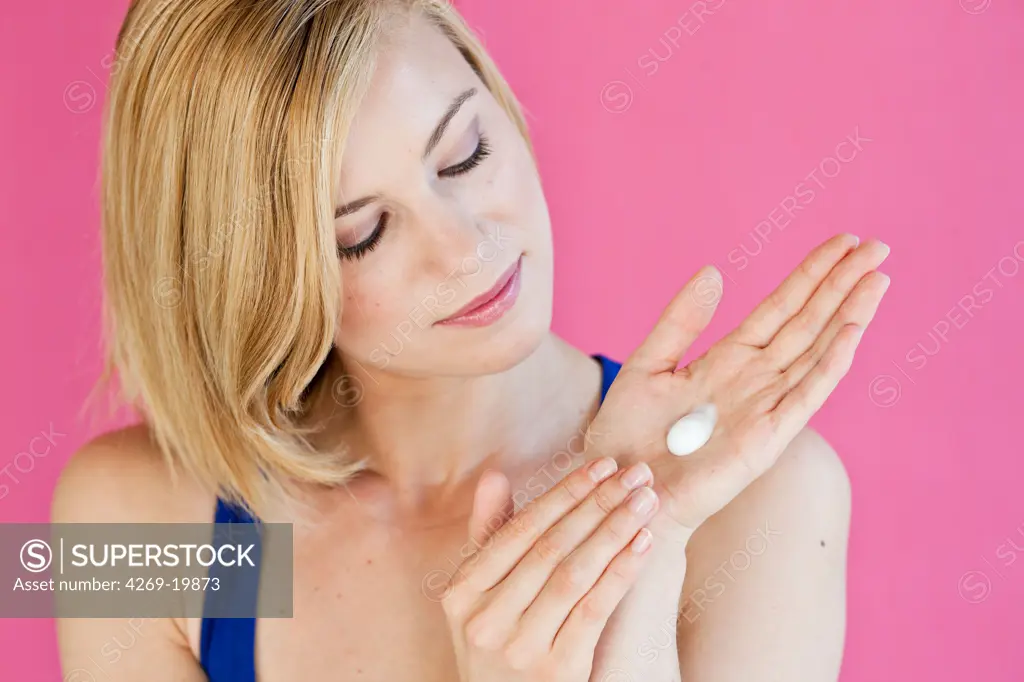 Woman applying moisturizing cream on her hands.