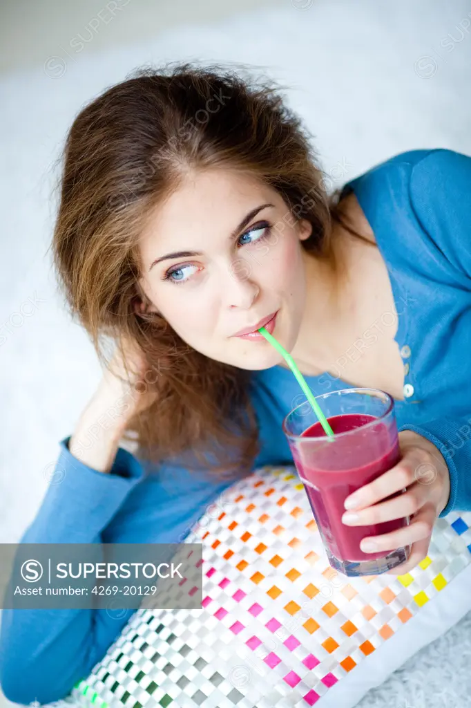 Woman drinking a smoothie (blended drink made from fruits).