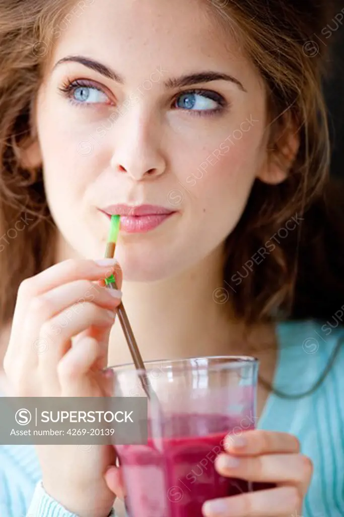 Woman drinking a smoothie (blended drink made from fruits).