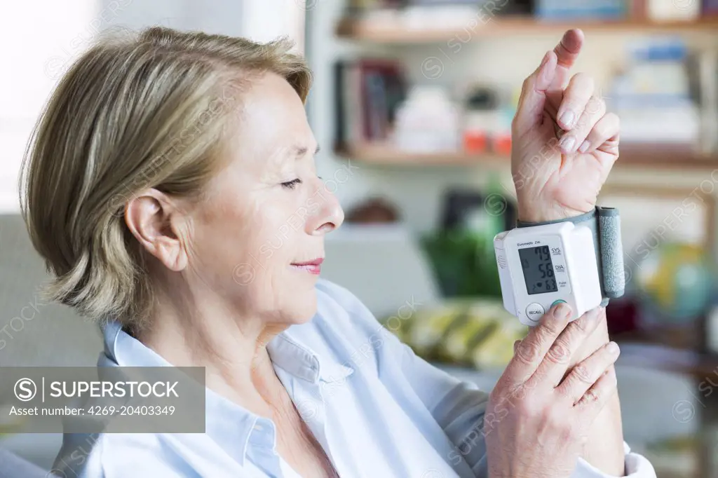 Woman taking her blood pressure with a portable blood pressure monitor.