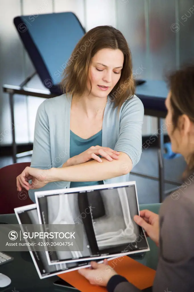Doctor examining and commenting patient's elbow X-ray.